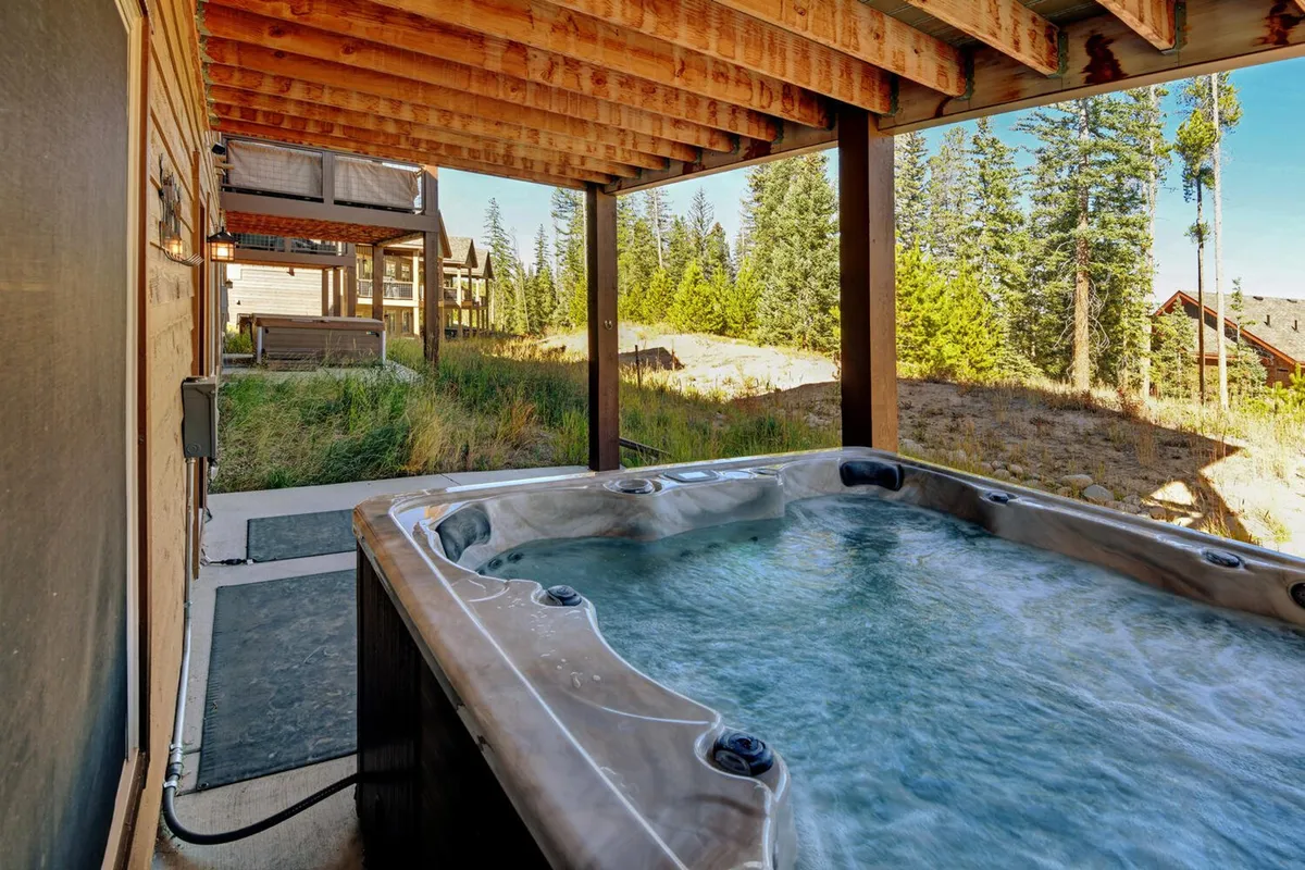 Set against natural surroundings, this image showcases a private hot tub nestled beside a wooden structure. The tranquil scene invites relaxation with sunset views or stargazing opportunities, suggesting a perfect retreat after a day of adventure.